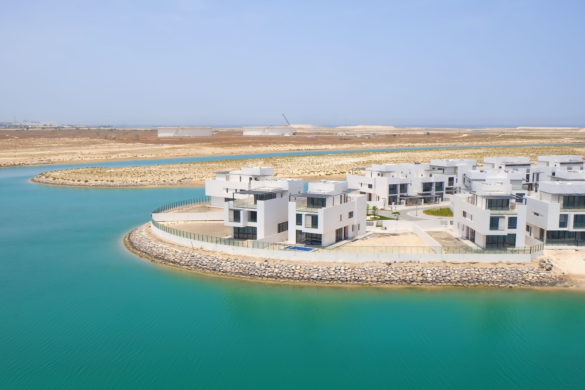 View of completion new waterfront villas neighborhood with direct access to beach. Luxury villas residential area under construction. Modern middle eastern urban architecture.