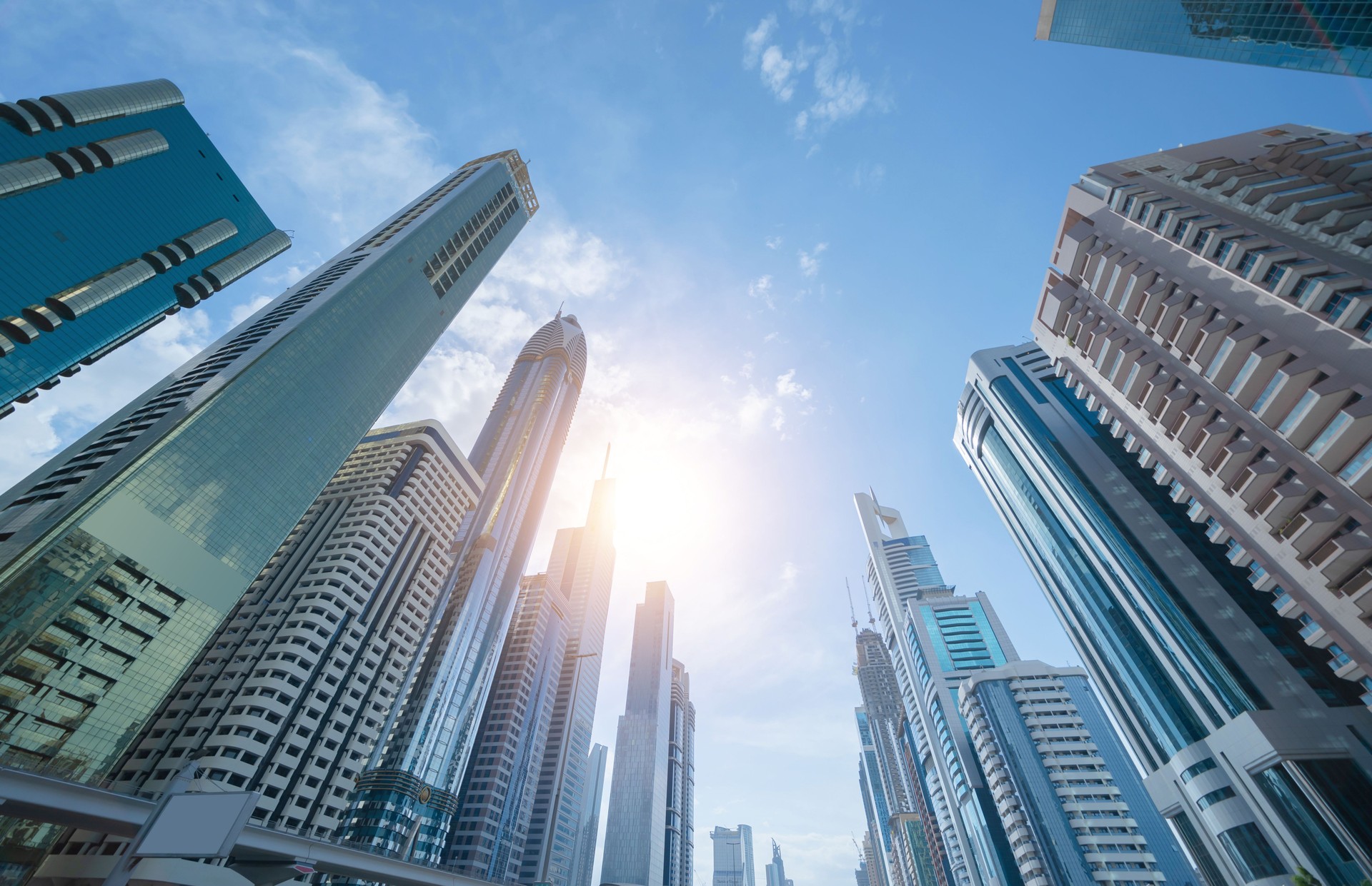 Looking up to high-rise office buildings, skyscrapers, architectures in financial district with blue sky. Smart urban city for business and technology concept background in Downtown Dubai, UAE.
